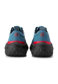 Modré semišové tenisky s texturovanou černou gumovou podrážkou, které mají červené akcenty a logo na patě. Šněrovací design s polstrovaným límcem.