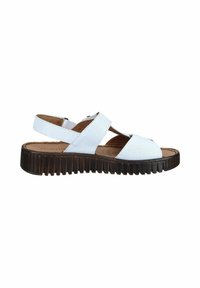 White perforated leather sandal with wide straps, adjustable back strap, cushioned tan footbed, and thick black grooved sole.
