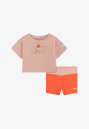 Conjunto juvenil de dos piezas con top corto de manga corta color durazno con texto de Nike y gráfico de helado, combinado con pantalones cortos naranjas con cinturilla rosa.