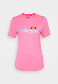 Camiseta rosa de manga corta confeccionada en algodón. Presenta el logo "ellesse" en plata con un detalle multicolor encima, cuello redondo y detalles en los hombros.
