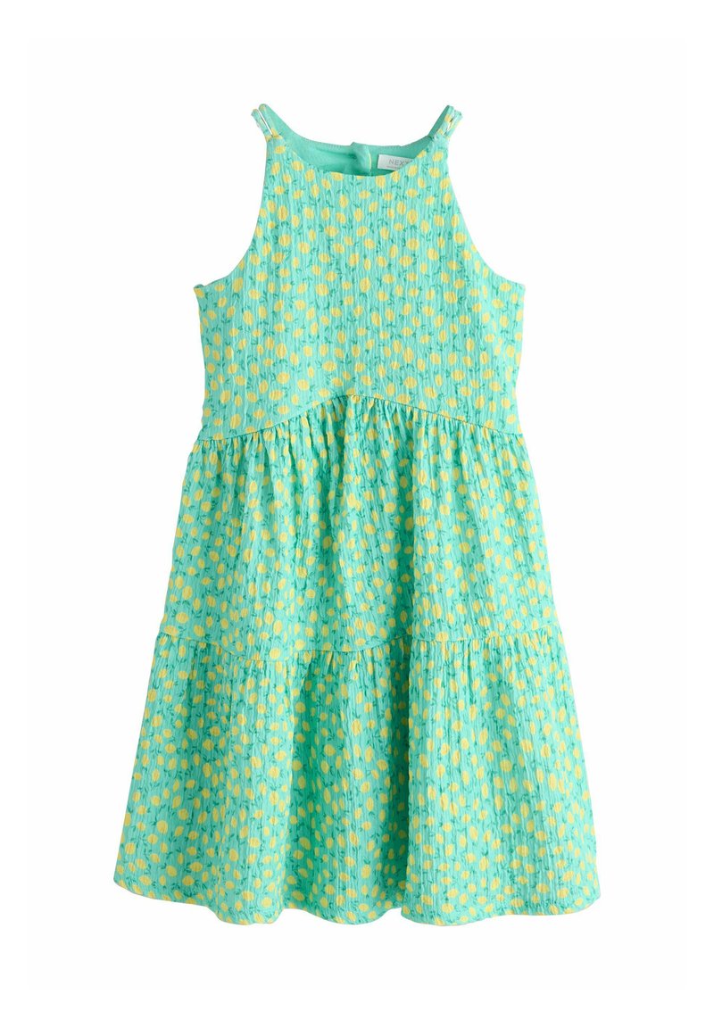 Egy ujjatlan, tókék színű ruha, amely réteges kialakítású, sárga pöttyökkel díszített, ráncolt mellrésszel, könnyű anyagból készült.