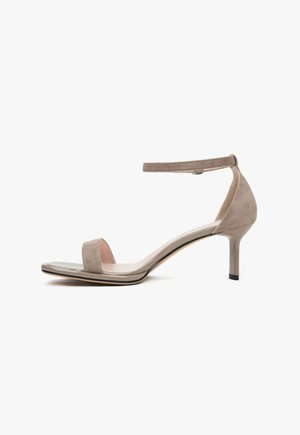 Beige Wildleder Absatzsandale mit einem Knöchelriemen, offenem Zehenbereich, glattem Lederfußbett und schlankem hohen Absatz. Minimalistisches Design.