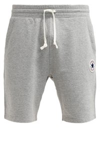Pantalones cortos de algodón grises con cinturilla elástica y cordón ajustable. Presentan un parche redondo de logo en el muslo izquierdo. Textura suave y diseño casual.