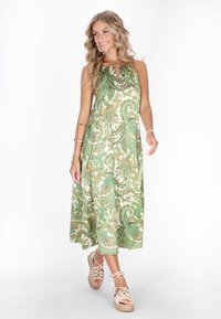 Rochie maxi cu imprimeu paisley verde și alb, cu decolteu drapat, detaliu cu slit și croială lejeră. Asortată cu espadrile cu bretele de culoare deschisă.