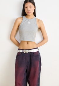 Gray ribbed crop top with a high neckline and small white logo, paired with dark red gradient wide-leg jeans and a studded white belt.