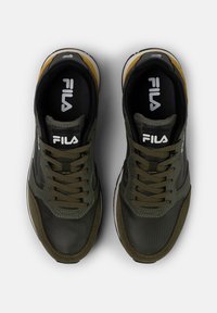 Grüne und schwarze Sportschuhe mit einem Obermaterial aus Mesh und Synthetik, runder Spitze, strukturierten Akzenten und kontrastierendem gelbem Absatz. Fila-Logo sichtbar.