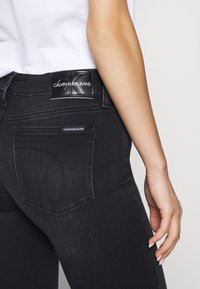 Svarta denimjeans med en figurnära design, med en synlig bakficka, Calvin Klein-logotyp patch och subtila sömdetaljer.