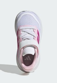 Balta sporta apavi ar rozā akcentiem, acs virskārta, apaļi pirksti un Velcro siksna. Redzama teksturēta zolīte un iekšpusē esošs logotips.