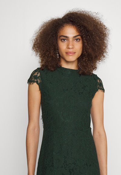 Πράσινο δαντελωτό φόρεμα με εφαρμοστή γραμμή, κοντά μανίκια και λουλουδάτα μοτίβα. Το ύφασμα έχει υφασμάτινη υφή και κυματοειδείς λεπτομέρειες στα μανίκια.
