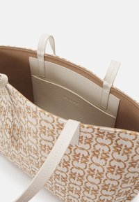 Sac fourre-tout beige et blanc avec motif floral marron, poignées en cuir crème et une poche intérieure étiquetée "PINKO."