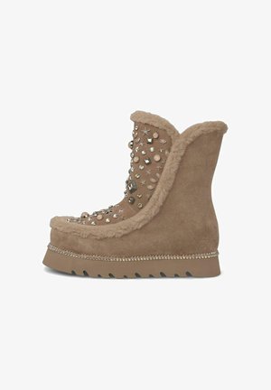 Tan suede boot with faux fur lining, embellished with various shaped studs and rhinestones. Features a wedge sole and decorative trim.