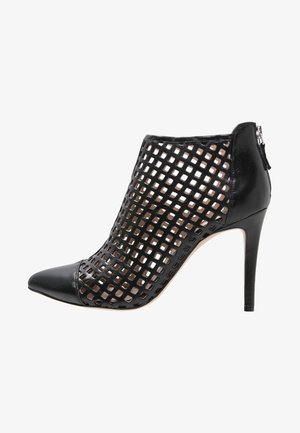 Bottine à talon haut noire avec un design en grille découpée, bout pointu et accents en cuir lisse. Dotée d'une fermeture éclair à l'arrière.