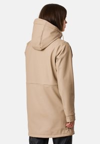 Manteau imperméable beige avec capuche, présentant une coupe décontractée, une texture lisse et un design minimaliste. Comprend un détail de couture au dos.