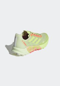 Chaussure de trail running vert clair avec lacets orange, trois bandes sur le côté, marquages "TERREX" et "300" et semelle robuste.