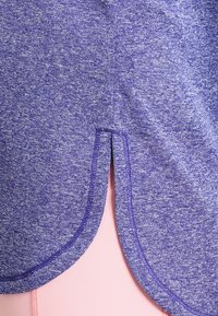 Lila träningslinne med en melerad textur, rundad fåll med sidoklämmor och kontrasterande sömmar längs kanterna.