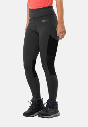 Black outdoor leggings with a high waistband and contrasting black panels. Paired with dark hiking boots featuring textured soles.