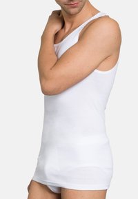 White cotton tank top with a crew neckline, slim fit, and wide shoulder straps, featuring smooth texture and no visible patterns or hardware.