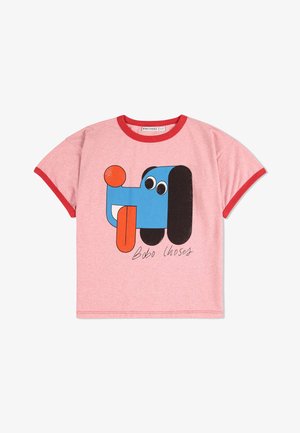 Camiseta de algodón rosa con ribetes rojos que presenta un gráfico de un perro de dibujos animados en azul, negro y naranja, con ojos grandes y la lengua afuera.