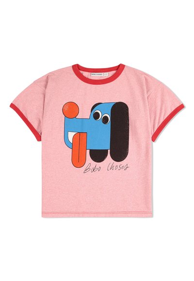 Lyserød bomulds t-shirt med rød kant, der har et cartoon-hunde grafik i blå, sort og orange, med store øjne og en tunge, der stikker ud.