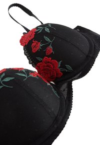 Reggiseno imbottito nero con ricami floreali rossi che rappresentano rose. La texture è liscia con bordo in pizzo e spalline regolabili per un maggiore supporto.