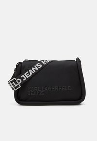 Fekete nejlon táska steppelt textúrával, cipzáros zárással és fényvisszaverő pánttal, amelyen a "KARL LAGERFELD JEANS" felirat található.