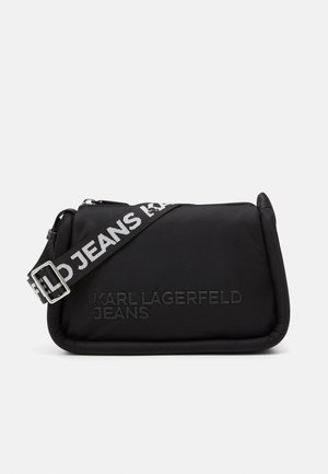 Schwarze Nylon-Tasche mit gestepptem Textur, ausgestattet mit einem Reißverschluss und einem reflektierenden Tragegurt, der "KARL LAGERFELD JEANS" liest.