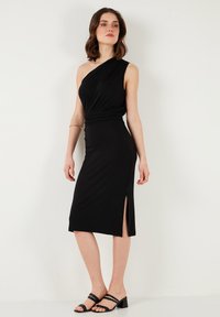 Black, one-shoulder dress with a fitted shape and side slit. Made of soft fabric, features gathered detailing at the waist. Accented with strappy sandals.