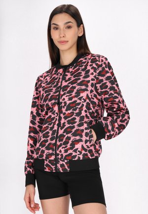 Giacca bomber con stampa leopardata rosa e nera, con chiusura a zip, polsini e orlo a costine. Indossata sopra pantaloni corti neri, presenta una vestibilità rilassata.