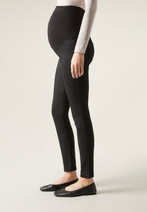 Graviditetsleggings i svart, med en högstretch midjeband, slim fit och slät yta. Matchas med svarta platta skor.