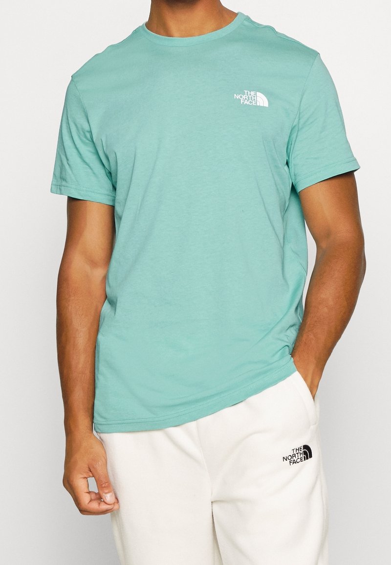 Jasnozielona koszulka z okrągłym dekoltem wykonana z miękkiego materiału. Posiada małe białe logo na lewej stronie klatki piersiowej oraz krótkie rękawy.