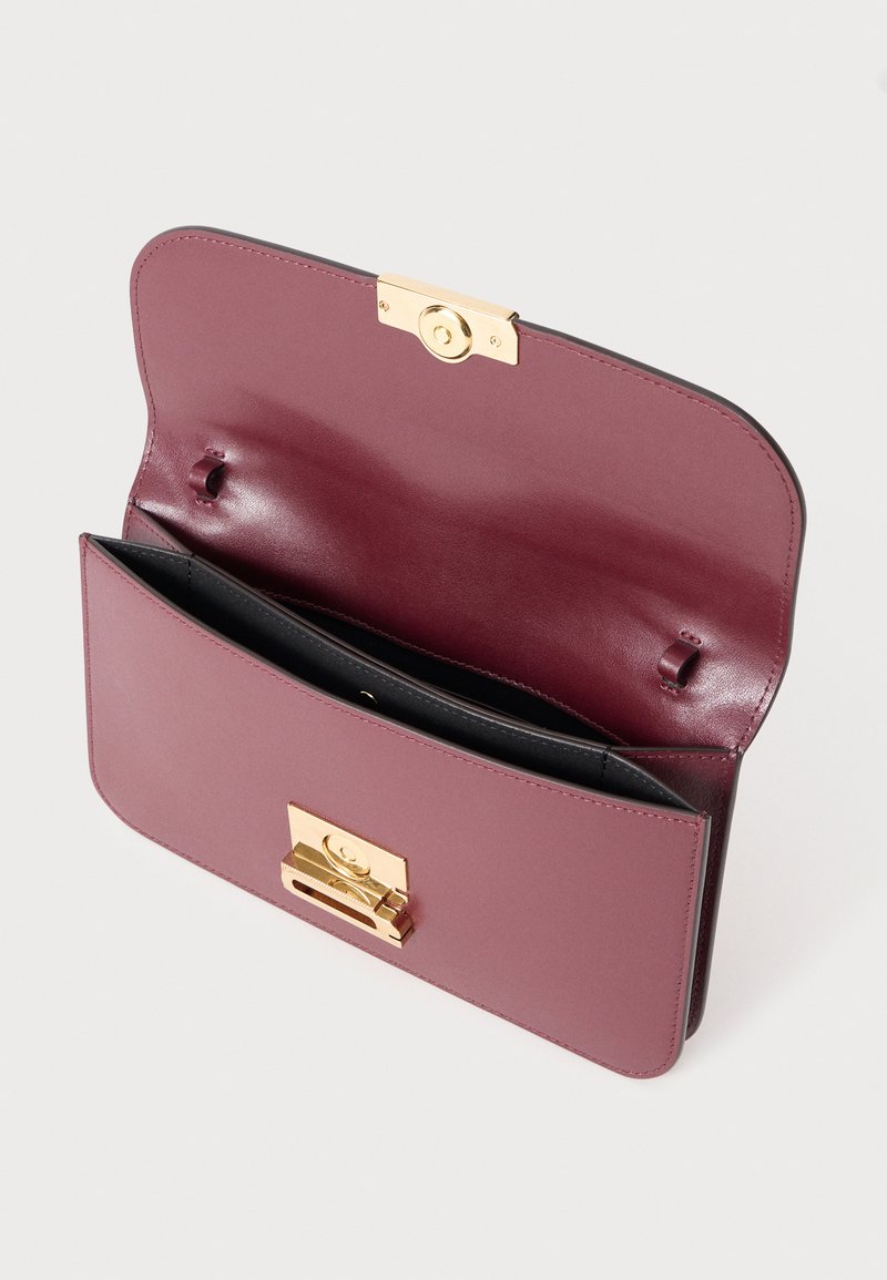 Sac à main en cuir bourgogne avec quincaillerie en or, présentant une forme rectangulaire, une fermeture à rabat et un compartiment intérieur avec une texture lisse.