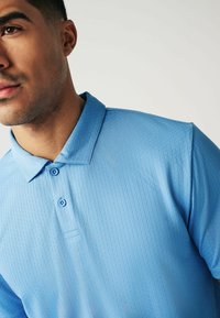 Himmelblaues Polohemd mit strukturiertem Muster, zwei Knöpfen am Kragen und einem klassischen Design, das sich gut für legere Kleidung eignet.