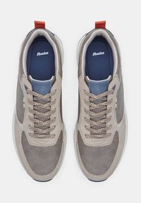 Hallidelt hallid suedsneakerid pruunide ja siniste aktsentide, tekstuursete ülekatetega, ringjate paelte ja valge kummitaldaga. Punane kannaosa. "Bata" logo sisetallal.