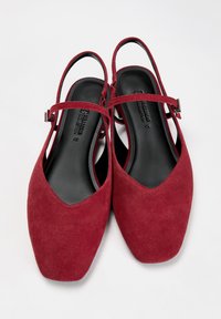 Rote Wildlederslingbacks mit spitzem Zehenbereich, einem verstellbaren Riemen und einer glatten schwarzen Sohle. Texturierte Oberfläche mit matter Verarbeitung.