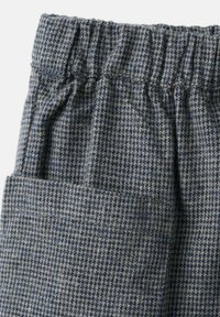 Tkanine hlače v modro-sivi karo vzorec. Imajo elastičen pas in stranski žep. Material se zdi teksturen in mehak.