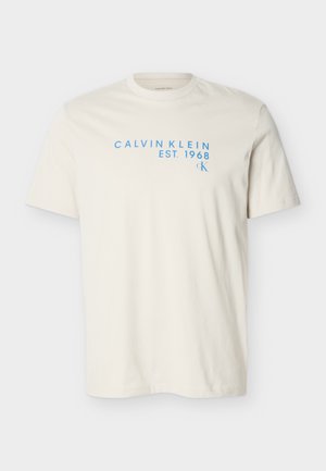Crèmekleurig T-shirt met korte mouwen en ronde hals, met lichtblauwe tekst "CALVIN KLEIN EST. 1968" en een klein "CK"-logo op de borst.