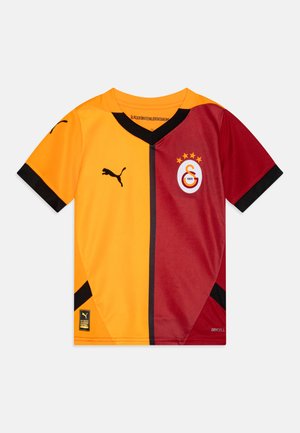 Maillot de sport Puma avec un design à découpe diagonale en orange et bordeaux, des accents noirs et un logo d'équipe avec quatre étoiles sur la poitrine.