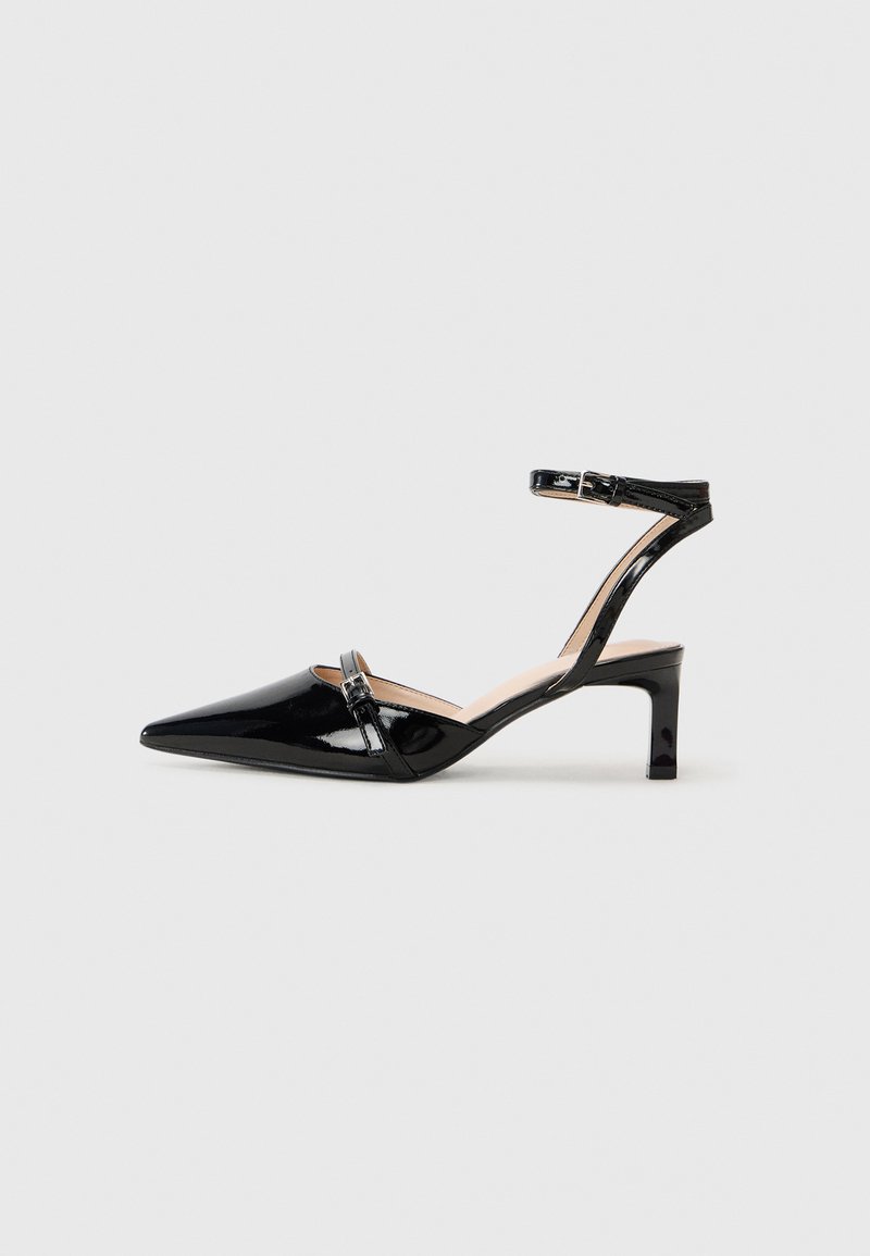 Tacchi slingback in vernice nera con punta affusolata, cinturino alla caviglia e tacco basso, caratterizzati da una delicata lavorazione degli strap.