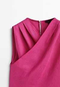 Haut sans manches en lin rose avec un design portefeuille, présentant des plis et une fermeture boutonnée au dos. Texture lisse avec un léger éclat.