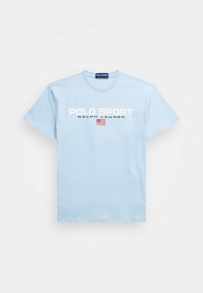 Gaiši zilas kokvilnas T-krekls ar apļa kakla izgriezumu, uz kura rakstīts "POLO SPORT" un "RALPH LAUREN" baltā tekstā, kā arī neliela Amerikas karoga grafika.
