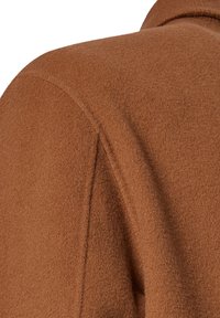 Brown wool coat featuring a textured finish, structured shoulder seam, and a soft drape. The fabric appears warm and cozy.