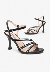 Schwarze High-Heelsandalen mit mehreren dünnen Riemen, verziert mit quadratischen Strasssteinen, einstellbarem Knöchelriemen und konturiertem Absatz.