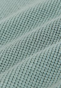 Gaiši zils tekstilmateriāls ar teksturētu, austu rakstu, uz kura redzamas slīpas rievas un gludas daļas. Mīksta sajūta ar elpojošu izskatu.