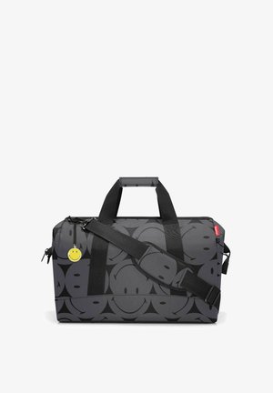 Schwarze Duffel-Tasche mit wiederholtem Smiley-Gesicht-Muster. Hergestellt aus strapazierfähigem Material, verfügt sie über zwei Tragetaschen und einen verstellbaren Schultergurt.