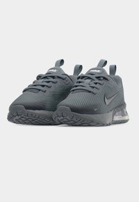 Ζευγάρι γκρι αθλητικά παπούτσια Nike Air Max με πλέγμα επάνω μέρος, κορδόνια, θηλιές τράβηγμα και ορατή αερόσολα στις σόλες, μπροστινή γωνιακή όψη.