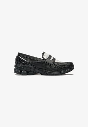 Mocassin basket noir avec tige en mesh et semelle rembourrée, combinant les styles de chaussure de sport et de chaussure à enfiler, présenté en profil latéral.