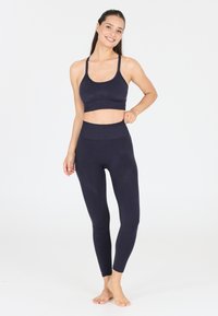 Marineblauer Sport-BH und Leggings-Set, hergestellt aus glattem, elastischem Material. Der BH hat dünne Träger; die Leggings haben einen hohen Bund und eine figurbetonte Passform.
