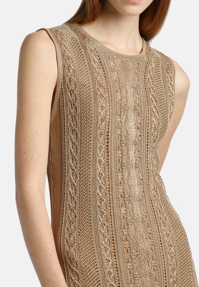 Robe sans manches tricotée en beige clair avec des motifs texturés, présentant des designs ajourés et un décolleté rond. Mi-longue avec une silhouette ajustée.