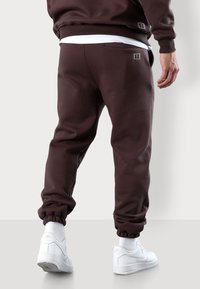 Braune Sweatpants mit elastischen Bündchen und einer lockeren Passform. Der Stoff wirkt weich, mit einem minimalistischen Design und dezenten Details an der Tasche.