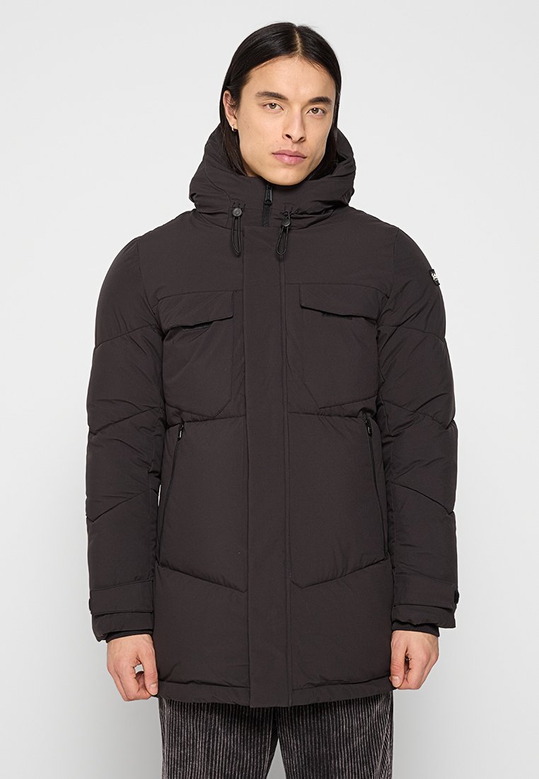 Veste noire matelassée avec capuche, dotée d'une fermeture éclair sur le devant, de poches sur la poitrine et sur les côtés, et d'un tissu texturé à finition lisse.